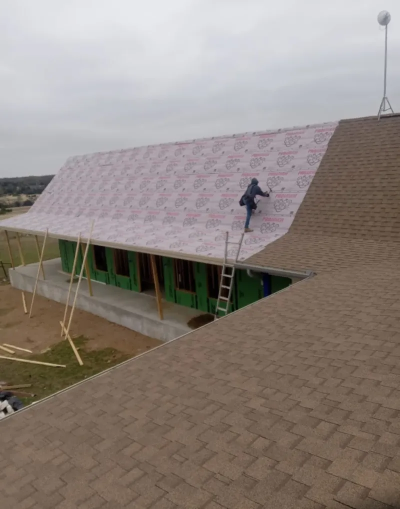 Worker preparing underlayment for a metal roof installation in Holly Springs